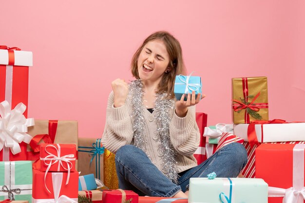 さまざまなプレゼントの周りに座っている正面図若い女性