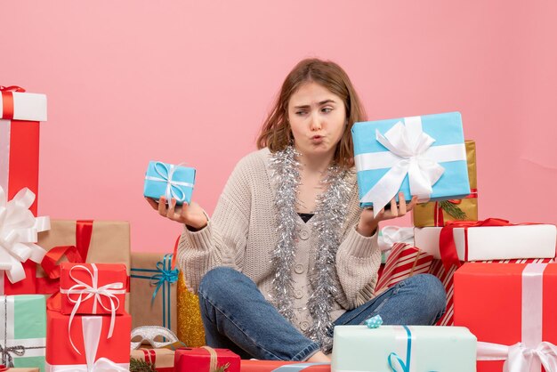 さまざまなプレゼントの周りに座っている正面図若い女性