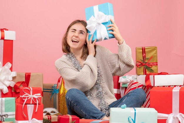 さまざまなクリスマスプレゼントの周りに座っている正面図若い女性