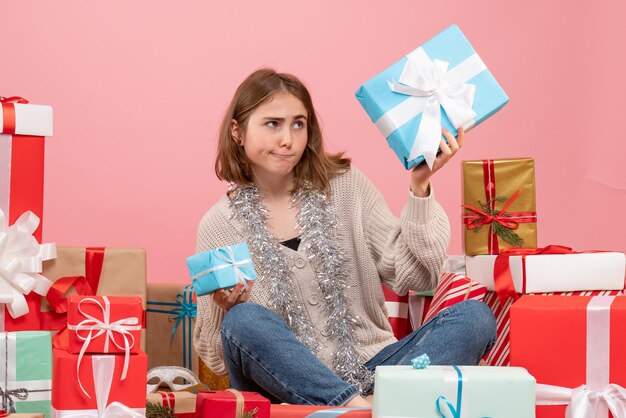 さまざまなクリスマスプレゼントの周りに座っている正面図若い女性