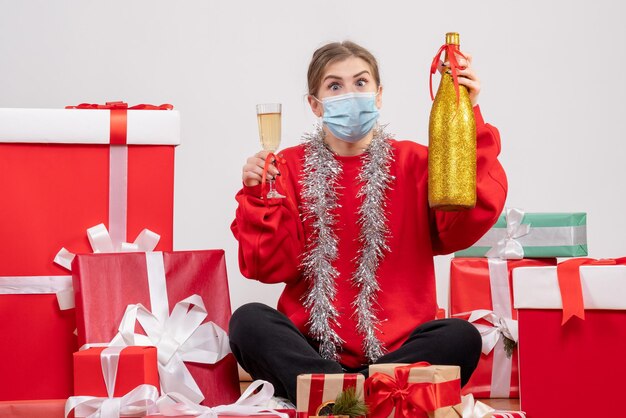 Front view young female sitting around presents celebrating with champagne