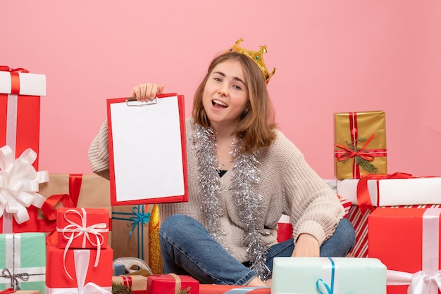 Front view young female sitting around presents with note in her hands