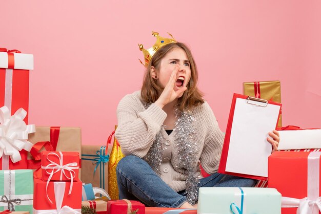 Front view young female sitting around presents with note in her hands