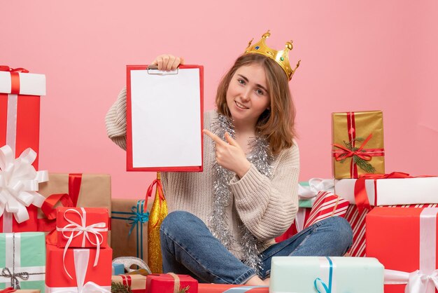 彼女の手にメモとプレゼントの周りに座っている正面図若い女性