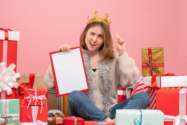 Front view young female sitting around presents with note in her hands