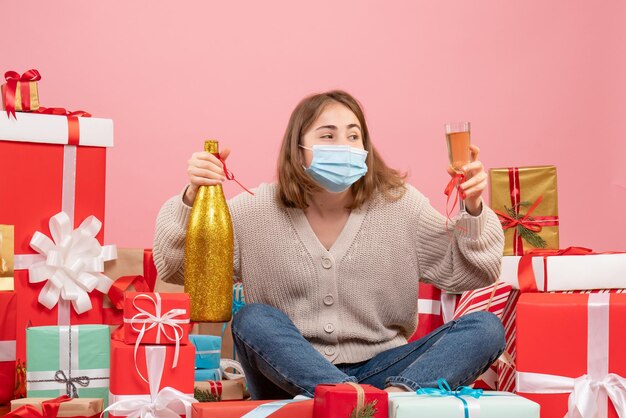 Front view young female sitting around xmas presents celebrating with champagne