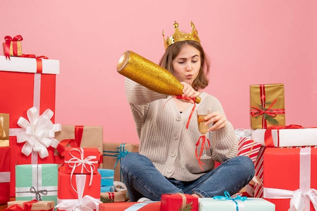 Front view young female sitting around xmas presents celebrating with champagne