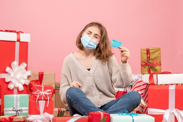 Front view young female sitting around xmas presents in mask