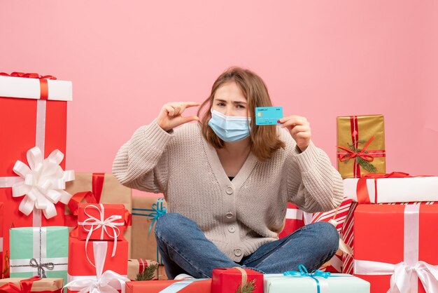 Front view young female sitting around xmas presents in mask