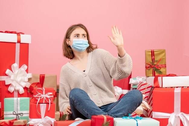 Front view young female sitting around xmas presents in mask