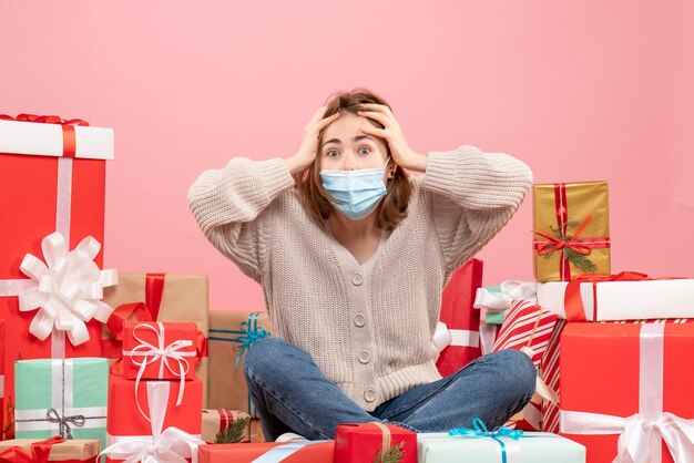 Front view young female sitting around xmas presents in mask