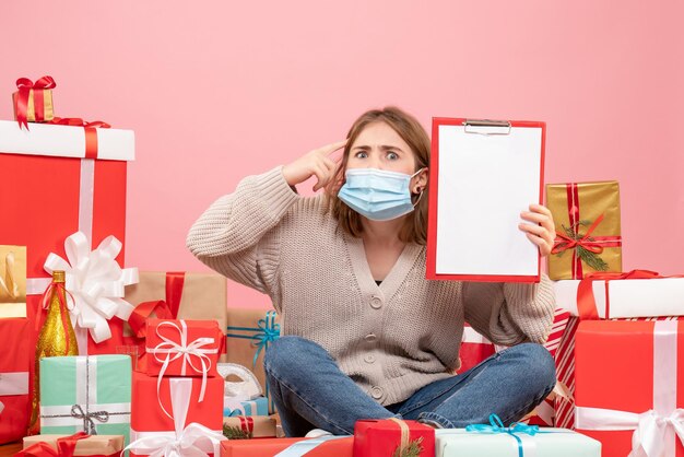 Front view young female sitting around xmas presents in sterile mask