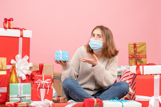 Front view young female sitting around xmas presents in sterile mask