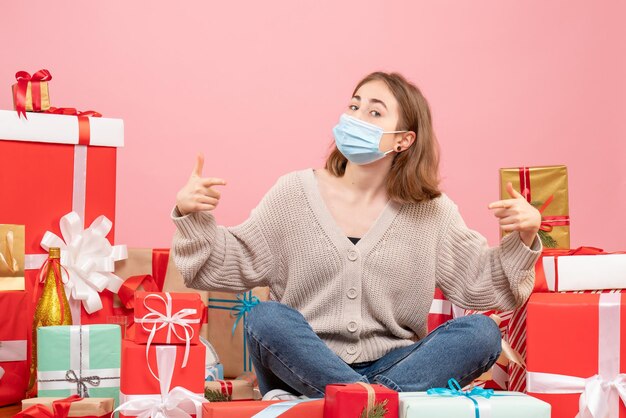 Front view young female sitting around xmas presents in sterile mask