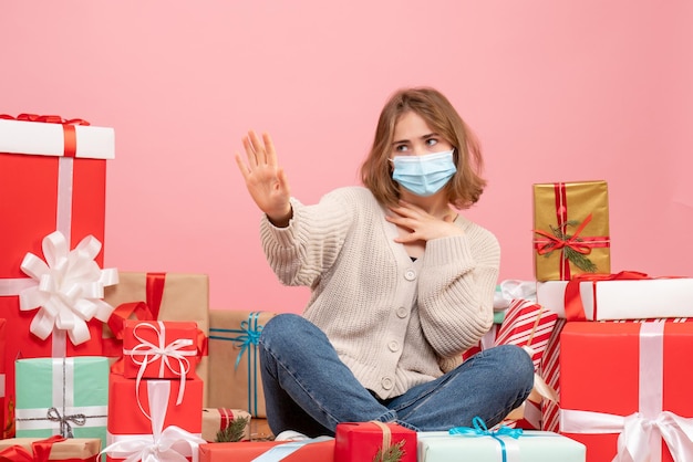 Front view young female sitting around xmas presents in sterile mask