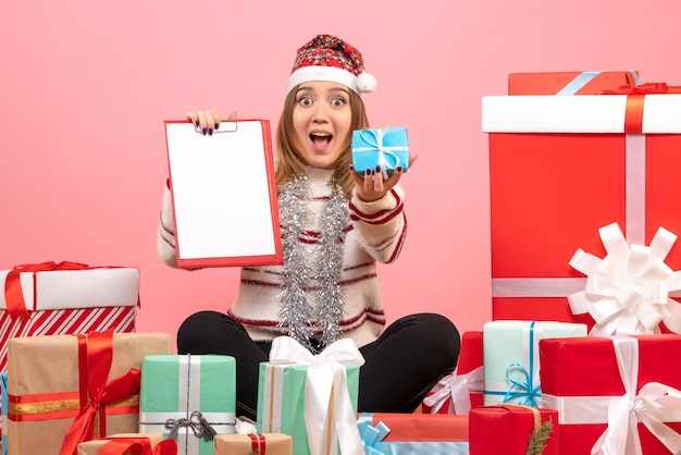 Front view young female sitting around xmas presents with file note