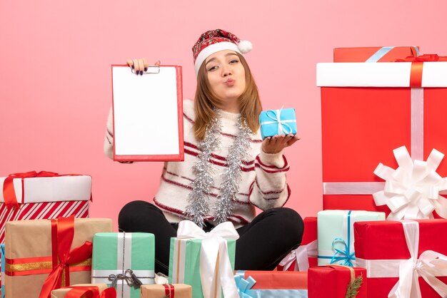 Front view young female sitting around xmas presents with file note