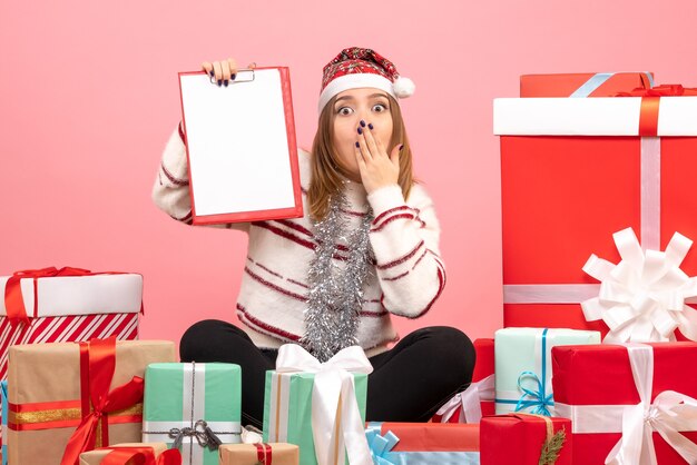 Front view young female sitting around xmas presents with file note