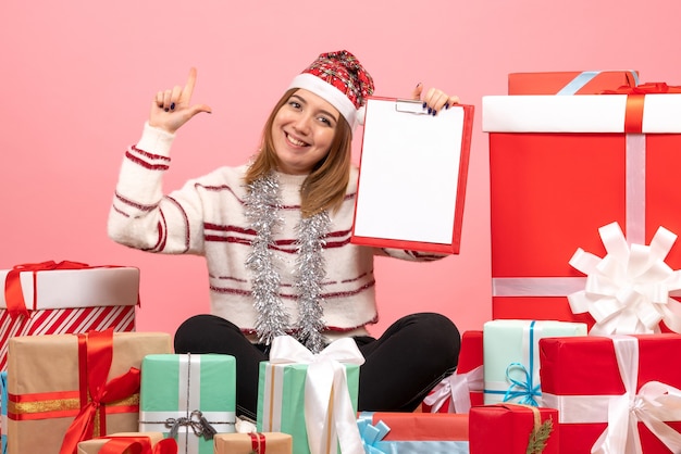 Front view young female sitting around xmas presents with file note