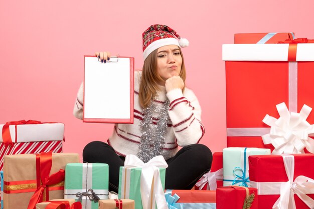 Front view young female sitting around xmas presents with file note