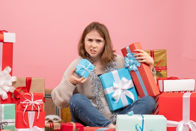 クリスマスプレゼントの周りに座っている正面図若い女性