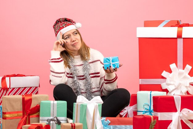 Вид спереди молодая женщина сидит вокруг рождественских подарков