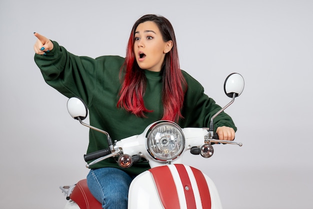 Front view young female sitting on motorcycle on white wall