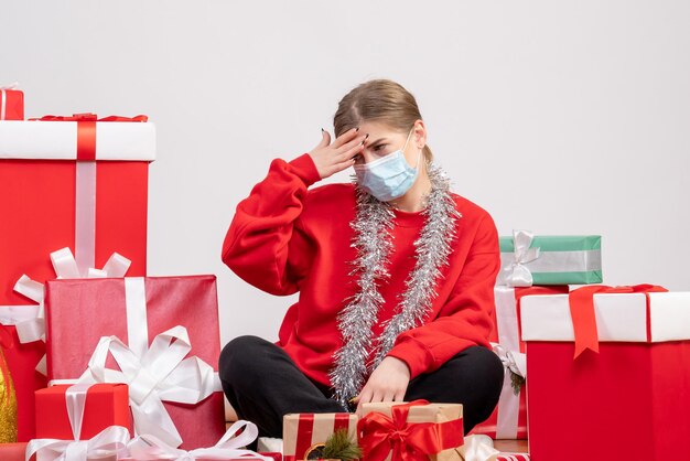 Front view young female sitting with christmas presents in mask