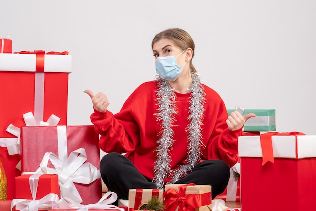 Front view young female sitting with christmas presents in mask