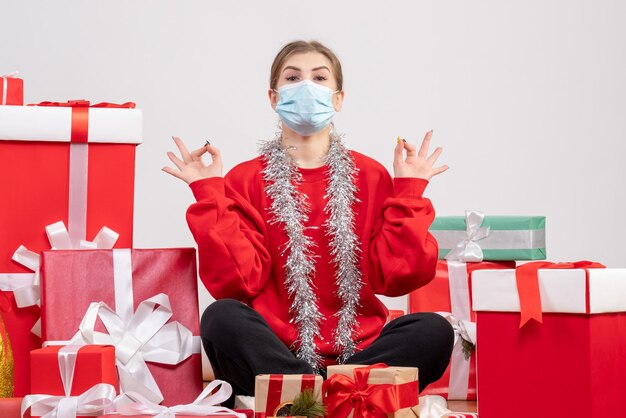 Front view young female sitting with christmas presents in mask