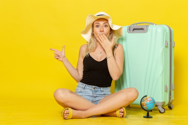Вид спереди молодая женщина, сидящая со своей сумкой на желтой стене, путешествие, путешествие, путешествие, путешествие, солнце