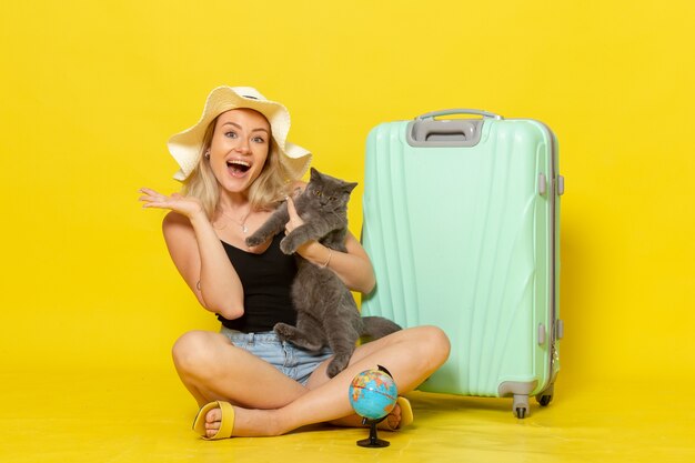 Front view young female sitting with her green bag holding kitten on the yellow wall trip vacation voyage sea journey sun