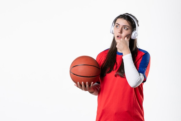 Вид спереди молодая женщина в спортивной одежде с баскетболом