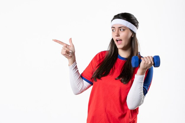 Front view young female in sport clothes with blue dumbbells on white wall