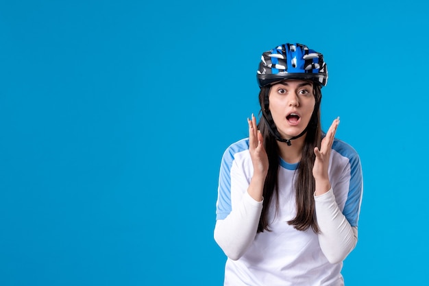 Front view young female in sport clothes with helmet on blue wall