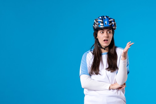 Front view young female in sport clothes with helmet on blue wall