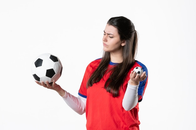 Front view young female in sport clothes with soccer ball on white wall