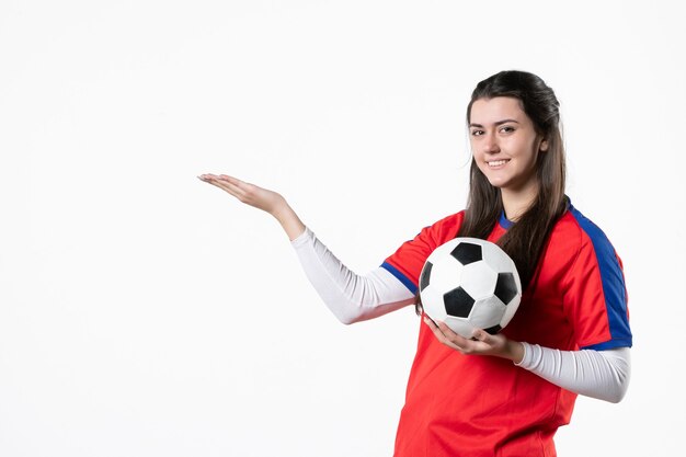 Front view young female in sport clothes with soccer ball on white wall