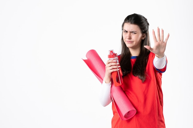 Front view young female in sport clothes with yoga mat on white wall