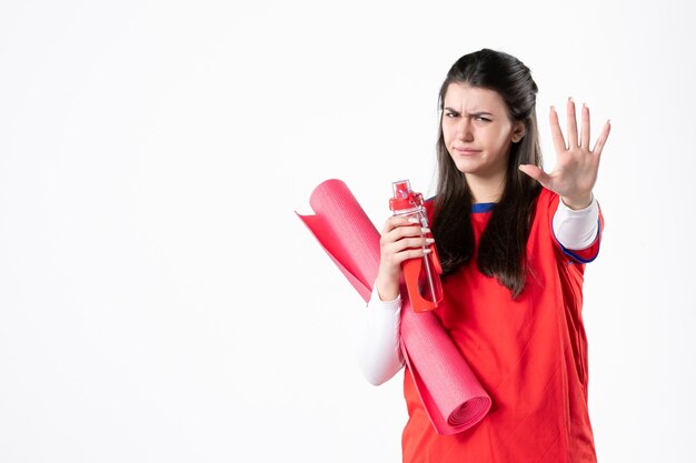 Front view young female in sport clothes with yoga mat on white wall