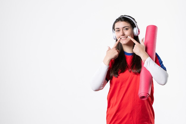 Front view young female in sport clothes with yoga mat white wall