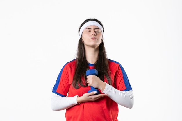 Front view young female in sport clothes working out with dumbbells on white wall