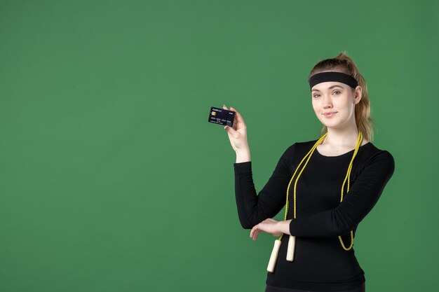 Front view young female in sport clothing holding bank card on green