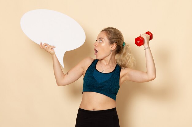 Front view young female in sport outfit holding dumbbells and white speech bubble