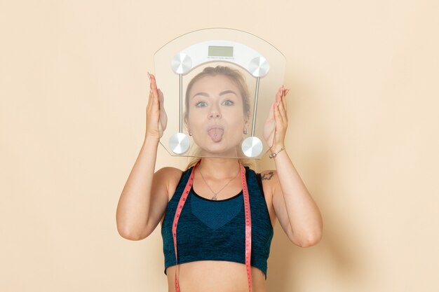 front view young female in sport outfit holding scales on white desk fit body sport beauty health exercises