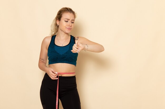 Front view young female in sport outfit measuring her body looking at her wrist