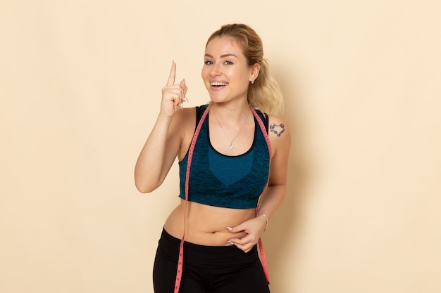 Front view young female in sport outfit measuring her body 