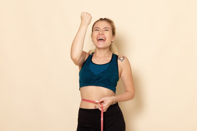 Front view young female in sport outfit measuring her sizes and waist