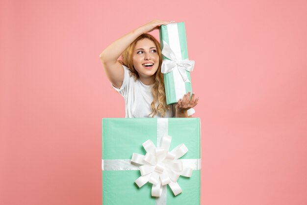 Вид спереди молодая женщина, стоящая внутри коробки, держащей подарок