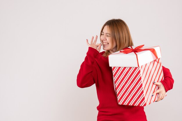 彼女の手にプレゼントボックスを持って立っている正面図若い女性